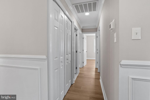 hall with ornamental molding and light wood-type flooring