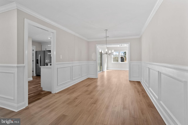 unfurnished dining area featuring light hardwood / wood-style flooring, ornamental molding, and a chandelier