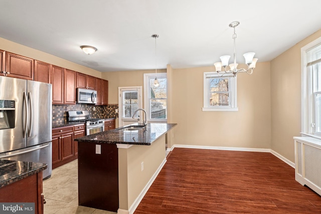 kitchen featuring radiator heating unit, pendant lighting, sink, tasteful backsplash, and stainless steel appliances