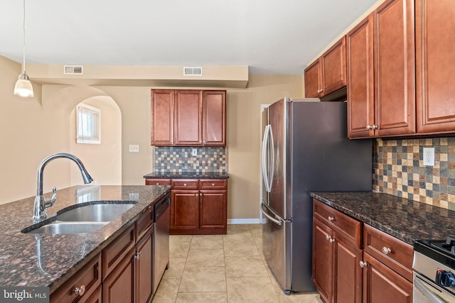 kitchen with hanging light fixtures, sink, tasteful backsplash, light tile patterned floors, and dark stone counters