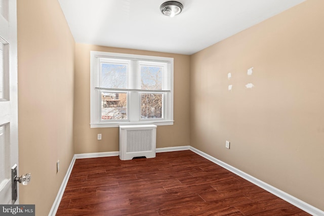 unfurnished room featuring radiator and dark hardwood / wood-style floors