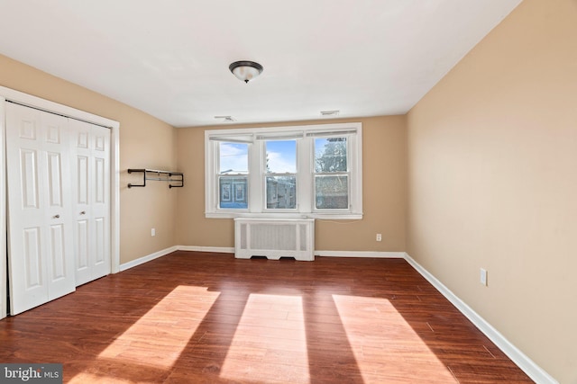 unfurnished bedroom with hardwood / wood-style flooring, radiator, and a closet