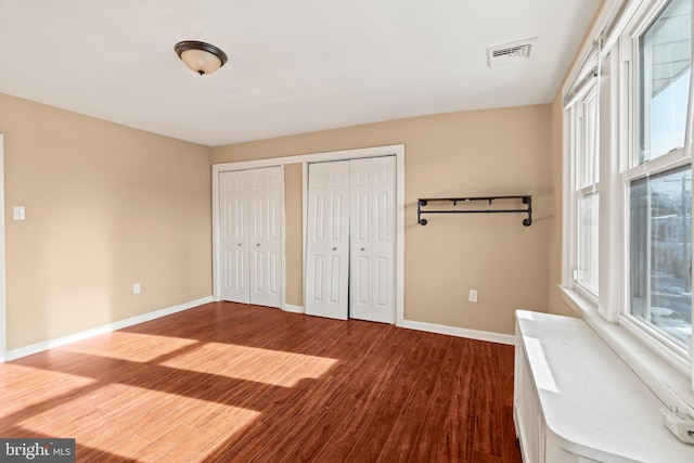 unfurnished bedroom with two closets and wood-type flooring