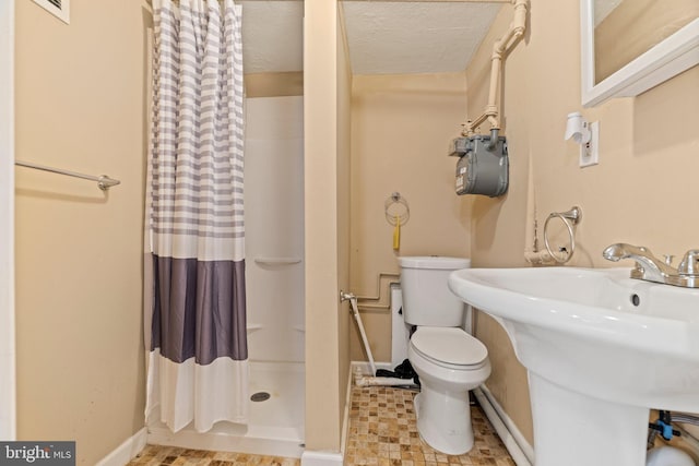 bathroom with a shower with curtain, toilet, sink, and a textured ceiling