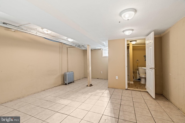 basement with radiator heating unit and light tile patterned flooring