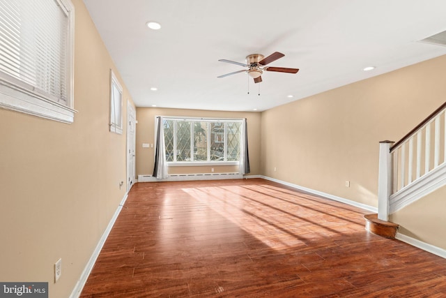 unfurnished living room featuring ceiling fan, baseboard heating, and wood-type flooring