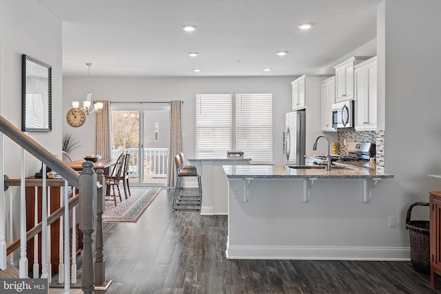 kitchen featuring appliances with stainless steel finishes, pendant lighting, white cabinets, and a kitchen bar