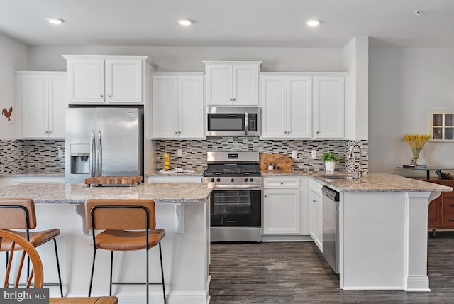 kitchen with stainless steel appliances, light stone countertops, sink, and white cabinets