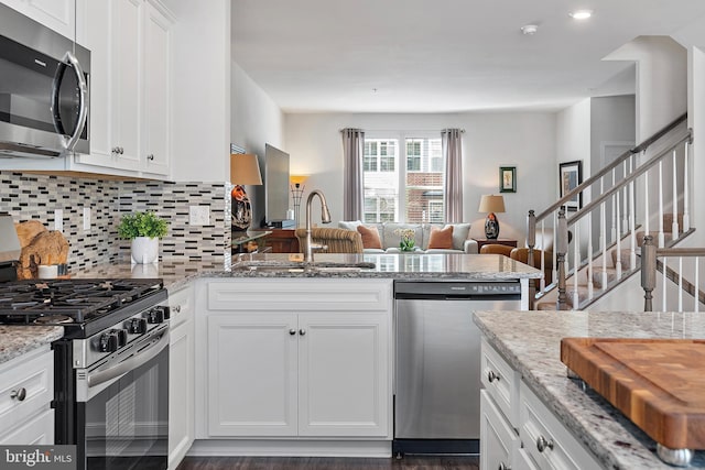 kitchen with white cabinetry, sink, backsplash, light stone counters, and stainless steel appliances