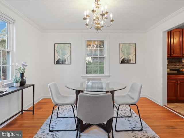 dining space with crown molding, light hardwood / wood-style floors, and a notable chandelier