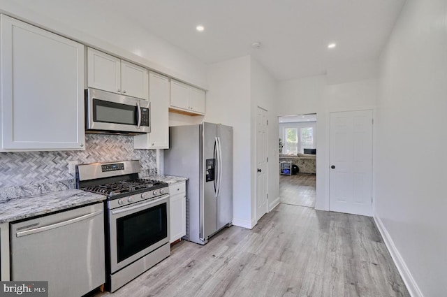 kitchen with white cabinets, stainless steel appliances, and light stone counters