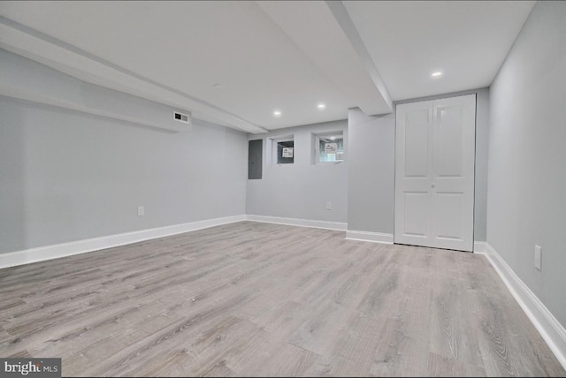 basement with light wood-type flooring and electric panel