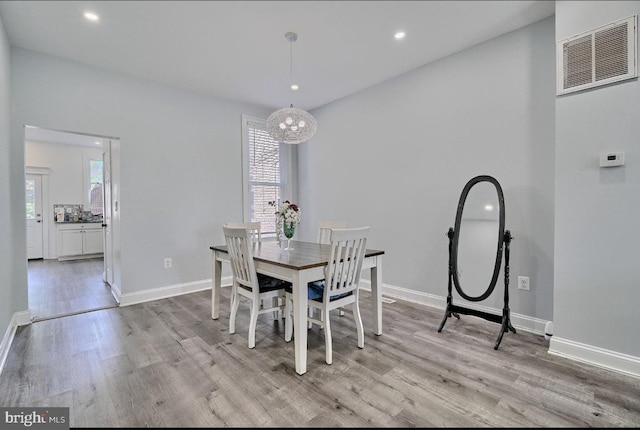 dining room with a wealth of natural light, light hardwood / wood-style flooring, and a notable chandelier