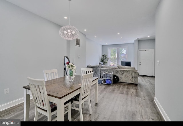 dining room with light wood-type flooring and a notable chandelier