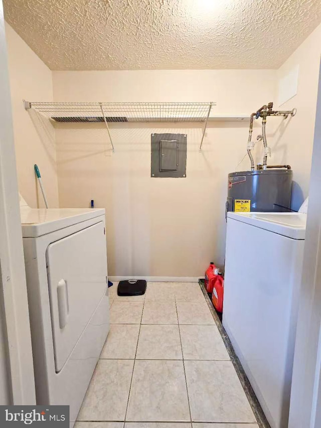 clothes washing area with tile patterned flooring, electric panel, electric water heater, washer and dryer, and a textured ceiling