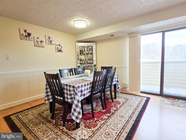 dining room featuring wood-type flooring and a textured ceiling