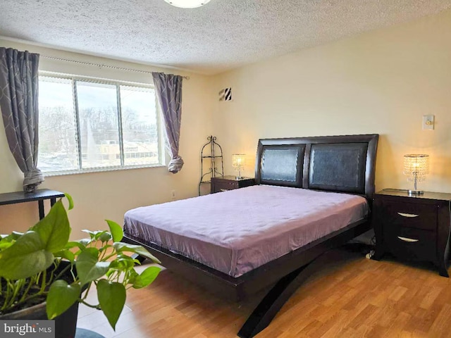 bedroom featuring light hardwood / wood-style floors and a textured ceiling