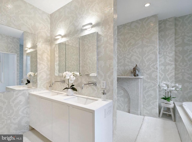 bathroom with tile patterned floors, tile walls, backsplash, a bath, and vanity