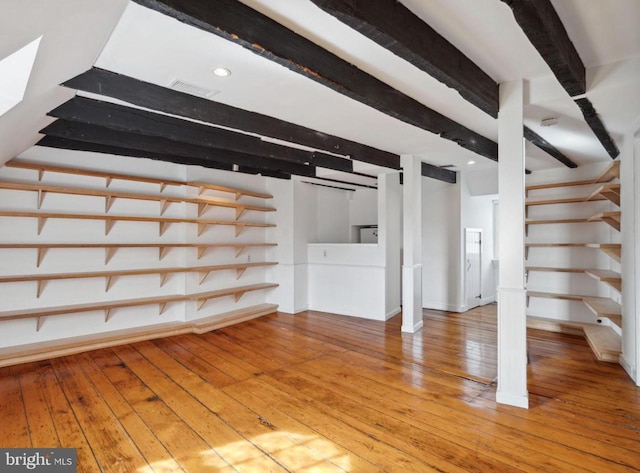 unfurnished living room with hardwood / wood-style flooring and beam ceiling