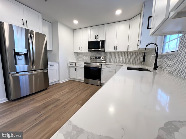 kitchen with light stone counters, stainless steel appliances, sink, and white cabinets