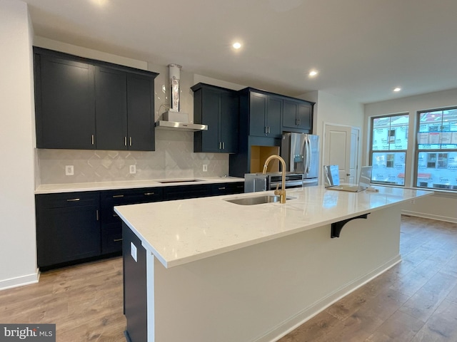 kitchen with stainless steel fridge with ice dispenser, a large island, light wood-type flooring, sink, and wall chimney exhaust hood