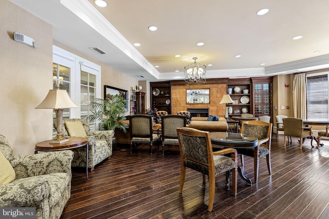 dining area with a raised ceiling, crown molding, dark hardwood / wood-style floors, and a notable chandelier