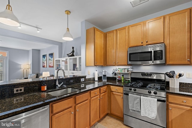 kitchen with light tile patterned flooring, sink, dark stone countertops, appliances with stainless steel finishes, and pendant lighting