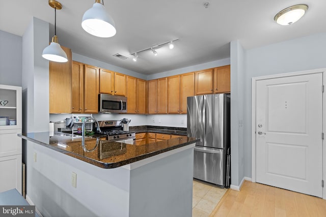 kitchen with pendant lighting, kitchen peninsula, dark stone countertops, and appliances with stainless steel finishes