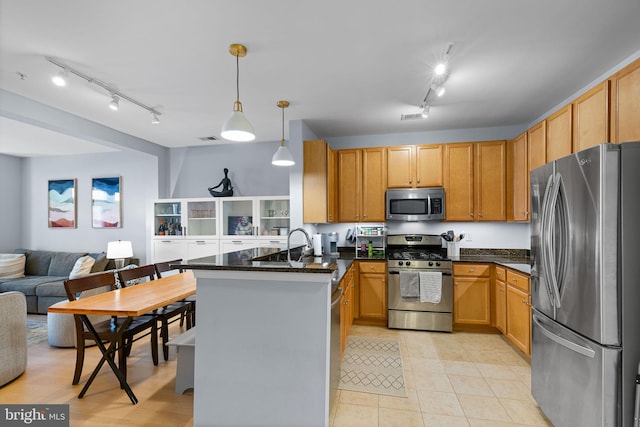 kitchen with light tile patterned floors, hanging light fixtures, stainless steel appliances, kitchen peninsula, and dark stone counters