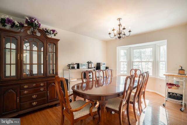 dining space with a notable chandelier and light hardwood / wood-style flooring