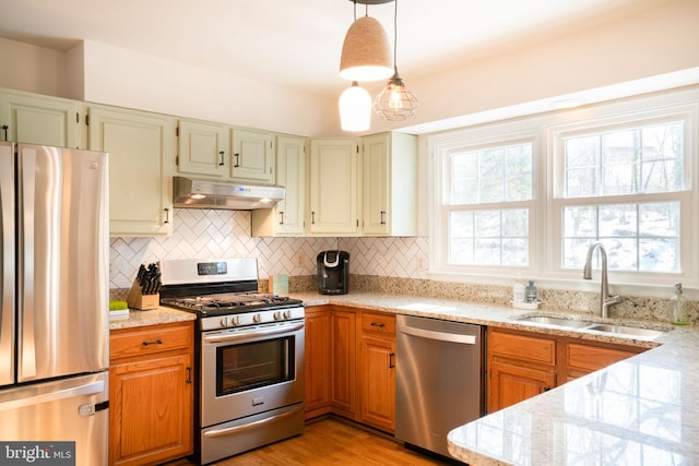 kitchen featuring sink, decorative light fixtures, appliances with stainless steel finishes, light stone countertops, and decorative backsplash