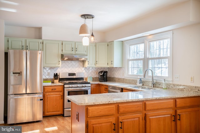 kitchen featuring pendant lighting, sink, stainless steel appliances, light stone counters, and kitchen peninsula