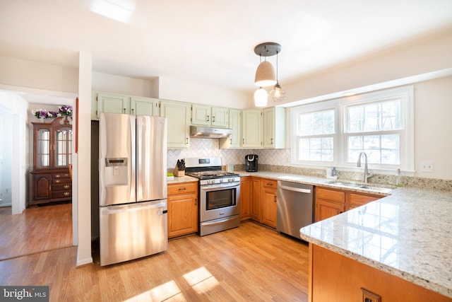 kitchen with decorative light fixtures, sink, decorative backsplash, light hardwood / wood-style floors, and stainless steel appliances