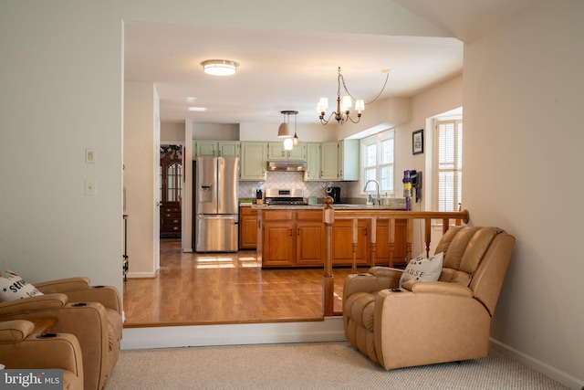 kitchen featuring a chandelier, hanging light fixtures, appliances with stainless steel finishes, green cabinets, and decorative backsplash