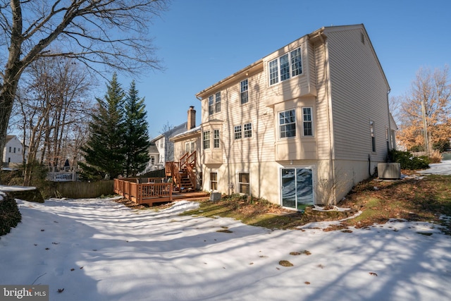 view of snowy exterior featuring a wooden deck and cooling unit