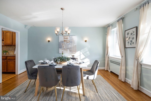 dining area featuring an inviting chandelier, radiator, and light hardwood / wood-style flooring