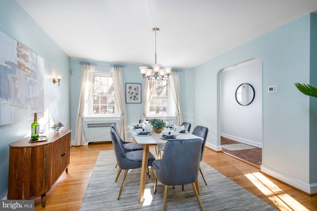 dining space with radiator heating unit, light hardwood / wood-style floors, and a notable chandelier