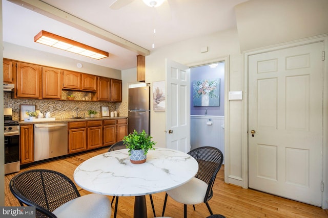 kitchen with appliances with stainless steel finishes, sink, decorative backsplash, ceiling fan, and light wood-type flooring