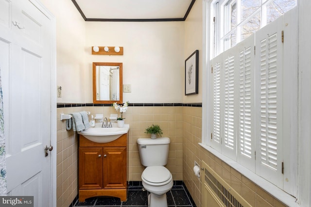 bathroom featuring crown molding, vanity, toilet, and tile walls