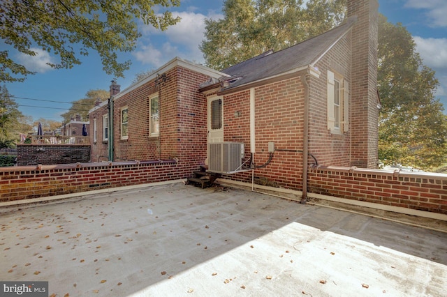 view of side of home with central AC unit and a patio