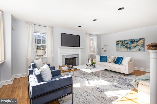 living room featuring a brick fireplace and light hardwood / wood-style flooring