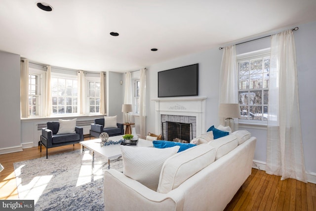 living room featuring plenty of natural light, a brick fireplace, and wood-type flooring