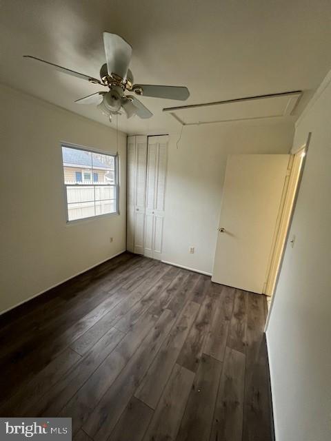 unfurnished bedroom with dark wood-style floors, a closet, and a ceiling fan