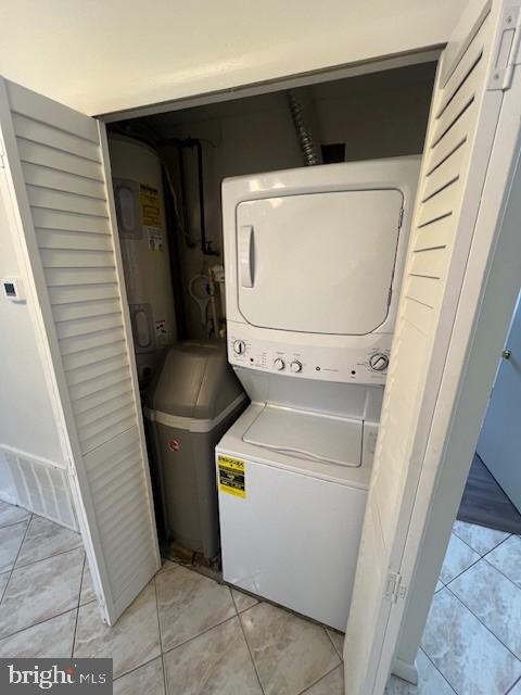 laundry room with laundry area, visible vents, stacked washer and clothes dryer, water heater, and light tile patterned flooring