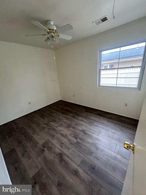 spare room with a ceiling fan, visible vents, and dark wood-style flooring