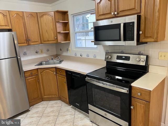 kitchen with decorative backsplash, brown cabinets, stainless steel appliances, light countertops, and a sink