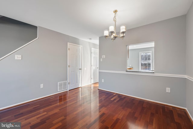 unfurnished room with dark wood-type flooring and an inviting chandelier