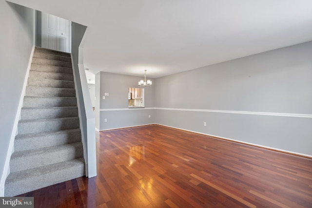 spare room with hardwood / wood-style floors and an inviting chandelier