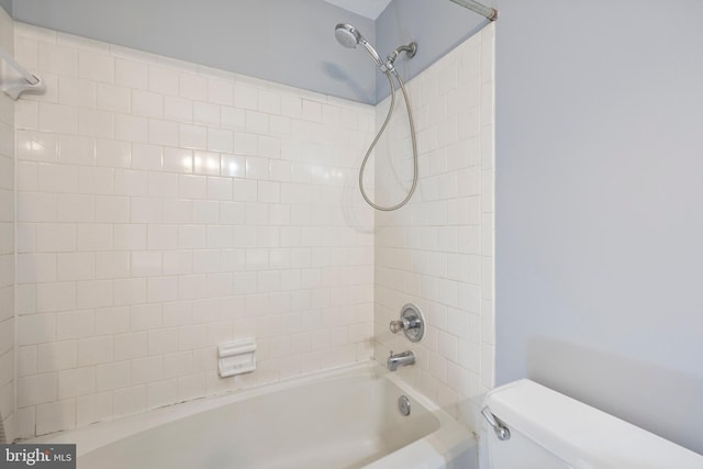 bathroom featuring tiled shower / bath combo and toilet