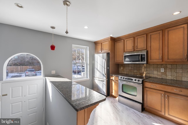 kitchen with decorative light fixtures, backsplash, dark stone countertops, and appliances with stainless steel finishes